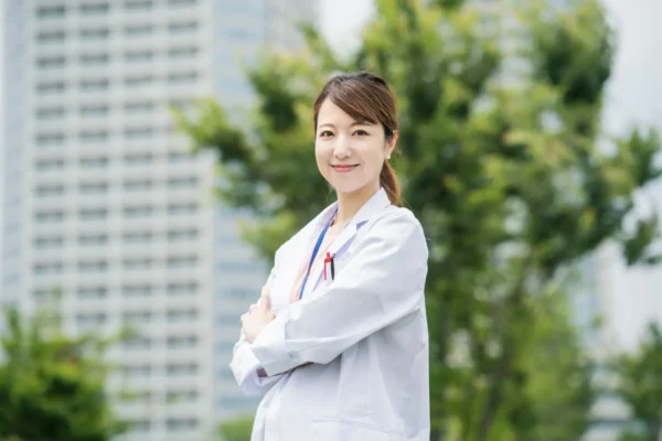 female doctor stands outside a building with her arms folded displaying health marketing